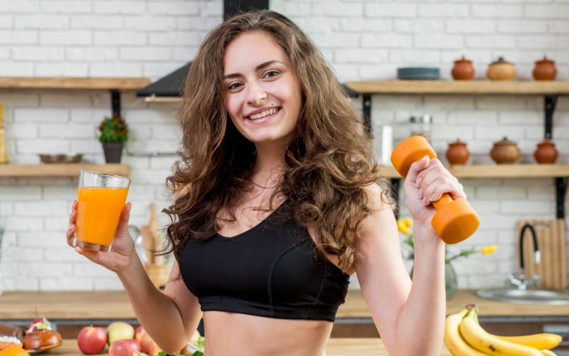 women with dumbbell and glass of juice